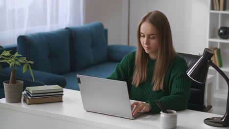 young-woman-is-working-with-laptop-in-living-room-surfing-internet-by-modern-notebook-using-social-nets-home-office
